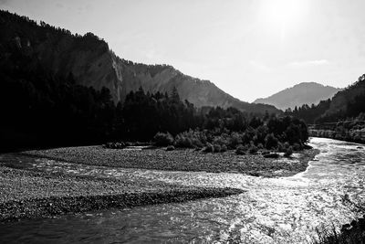 Scenic view of river by mountains against sky