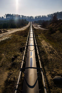 Metal bridge over field against sky