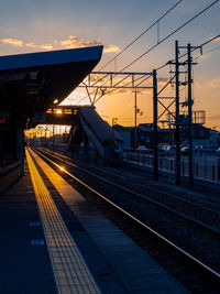 Railroad station against sky at sunset