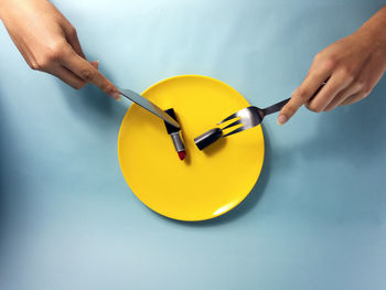 Close-up of person eating lipstick with knife and fork