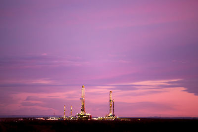 Drilling rig on field against cloudy sky