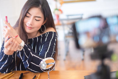 Young woman looking away while sitting on table