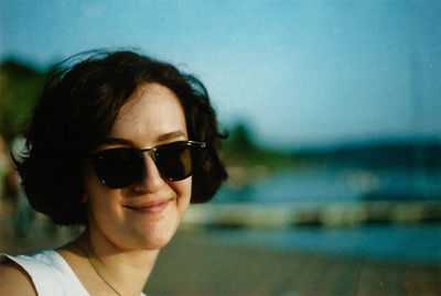 Portrait of smiling young woman in sunglasses against sky