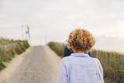 Rear view of woman walking on road against sky