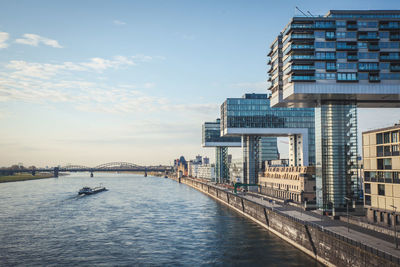 Bridge over river amidst buildings in city against sky