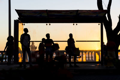 Silhouette of people at a bus stop.