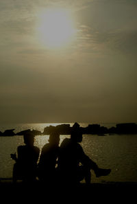 Silhouette of people in sea at sunset