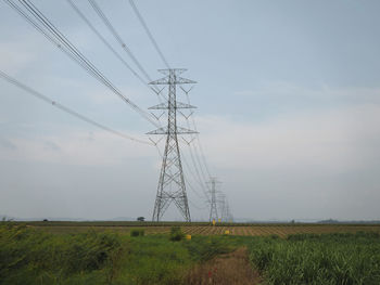 Electricity pylon on field against sky