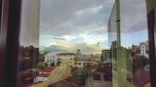 Buildings against sky seen through glass window