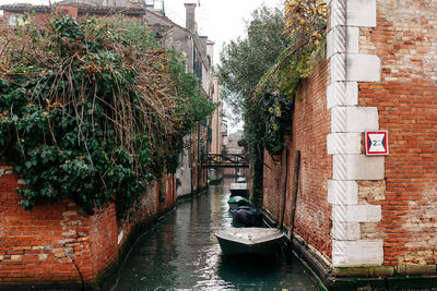 Boats moored in canal amidst buildings