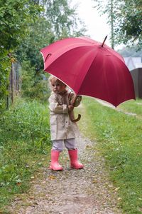 Girl holding umbrella standing on wet rainy day
