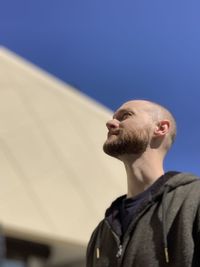 Low angle view of man looking away while standing against sky