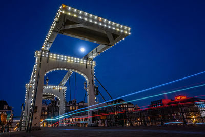 Low angle view of illuminated bridge against blue sky