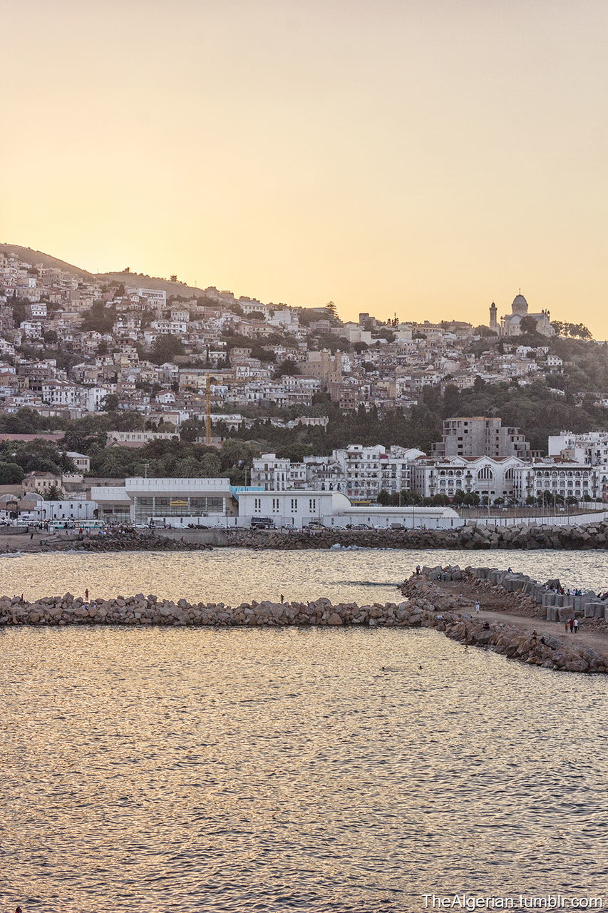 building exterior, architecture, built structure, cityscape, city, residential structure, water, clear sky, residential building, residential district, river, copy space, waterfront, house, town, sunset, sky, townscape, high angle view, crowded