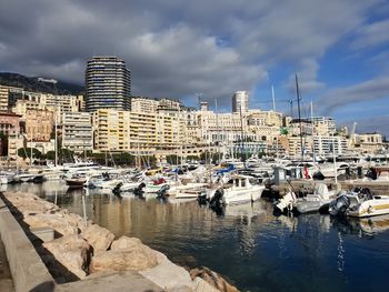 Boats moored at harbor against buildings in city