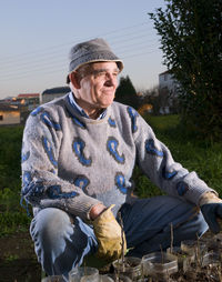 Smiling man crouching on field against sky