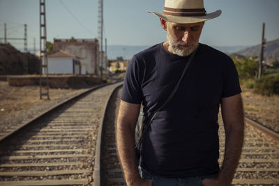 Adult man in jeans carrying bag walking on railway track