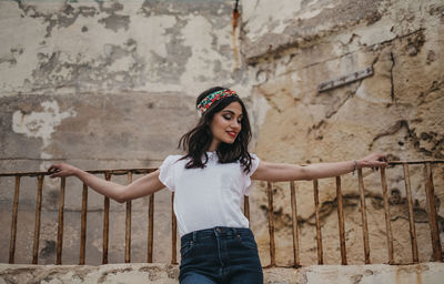 Portrait of young woman standing against wall