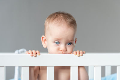 Portrait of cute baby boy sitting on bed at home