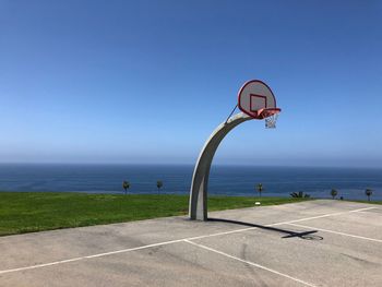 Basketball hoop by sea against clear sky