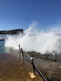 Water splashing in sea against clear sky