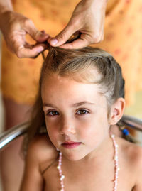 Cropped hands of mother braiding daughter hair