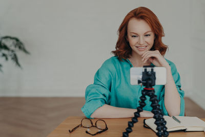 Portrait of smiling woman holding camera at home