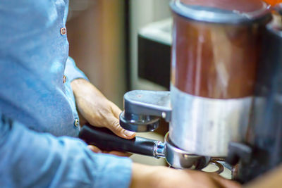 Close up barista is grinding freshly roasted by coffee grinder make beans into a powder.