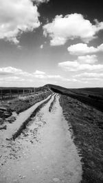 Road amidst field against sky