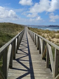 Wooden footbridge on footpath against sky