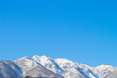 Scenic view of snowcapped mountains against clear blue sky