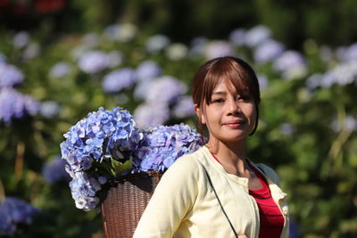 Portrait of smiling young woman against purple flowering plants in farm