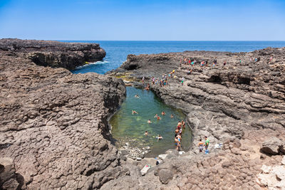 High angle view of people enjoying swimming in sea against sky