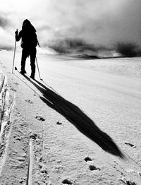 Rear view of people skiing on snow covered field