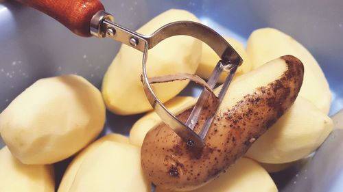 High angle view of potatoes and peeler