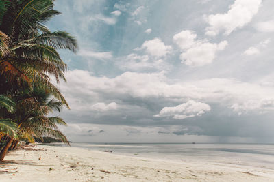 Scenic view of beach against cloudy sky