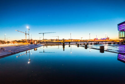 Reflection of illuminated buildings in water against clear sky