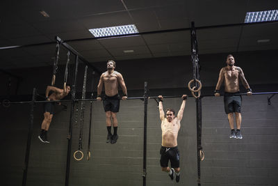 Athletes doing pull ups exercise on rod at gym