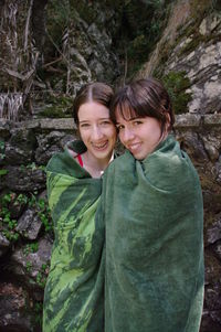 Portrait of female friends wrapped in green towel against rock formations