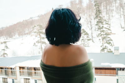 Rear view of woman standing in balcony against snow covered land