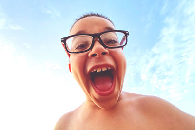 Portrait of shirtless young man wearing eyeglasses against sky