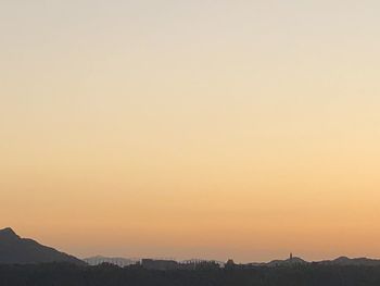 Scenic view of silhouette mountains against orange sky