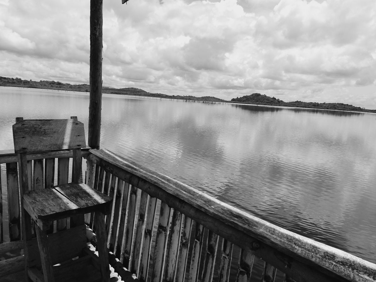 VIEW OF WOODEN RAILING BY LAKE AGAINST SKY