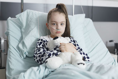 Portrait of cute girl sitting on bed at home