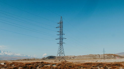 Electricity pylon on field against clear sky