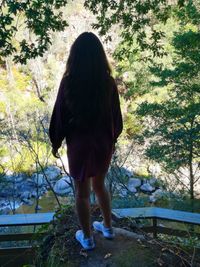 Rear view of woman standing against trees