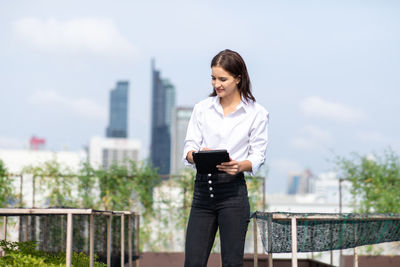 Young woman using mobile phone against cityscape