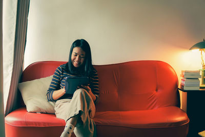 Young woman sitting on sofa at home