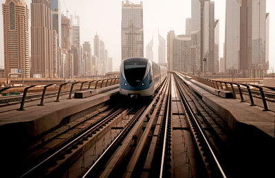 Railroad tracks in city against sky