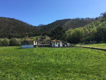House on field by trees against sky